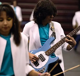 Percussion performers playing guitar in white suits